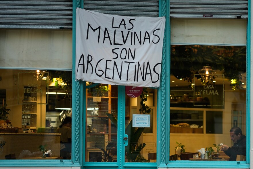 A man sits at a restaurant displaying a banner reading "The Malvinas are Argentine," referring to the Falkland Islands, also known as Malvinas, in Buenos Aires, Argentina, Monday, July 27, 2026.