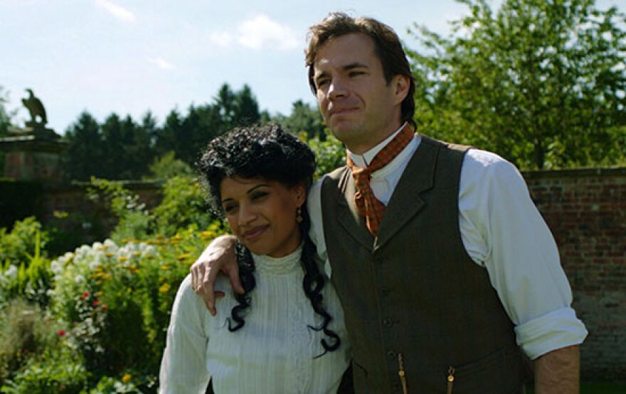 A man and a woman embrace in period clothes