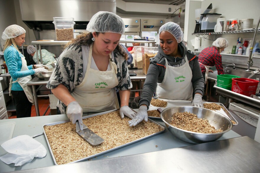 Jenyka Gassnola, an intern, and Hanna Teklu, a graduate of the program and now a program assistant, smooth out the granola before it goes to the oven to bake.