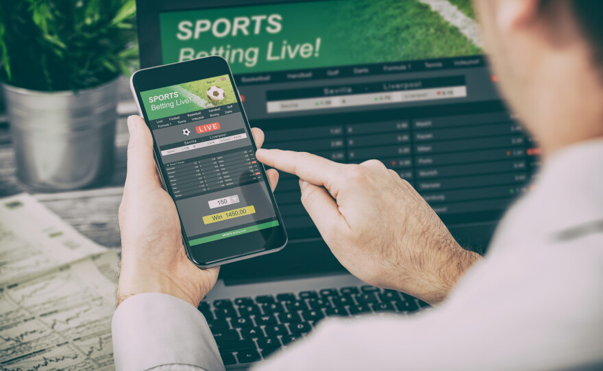 This stock image shows a man using his cellphone to access a sports betting site.