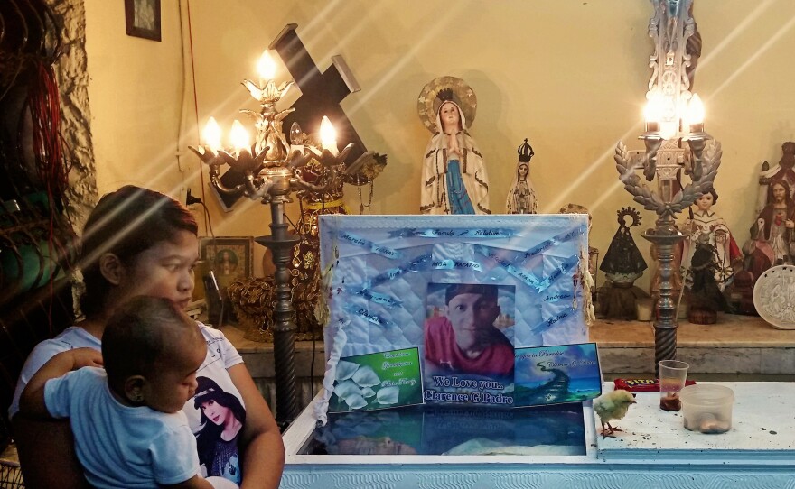 Clarence Jepadre's girlfriend Rachel Quebec stands with daughter Roseann in front of his casket. A chick paces on the coffin's lid. Jepadre, 17, was found stabbed to death. It's a tradition to place chicks on the coffins of murder victims to peck at the conscience of the killer.
