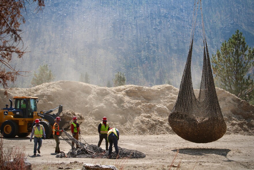  Workers help attach bulging nets full of mulch to waiting helicopters, which then drop the payload on areas burned by the Cameron Peak Fire. The mulch helps stabilize charred soil, keeping debris from flowing into the nearby river.