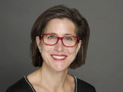 Kelly McBride press photo - woman with brown hair and red-rimmed glasses