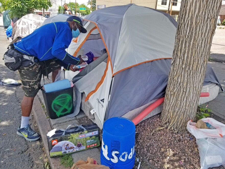 David Scott loads supplies into his tent home in downtown Denver. "As long as they keep it to where we're getting cleaned, not swept, it's all right," says Scott.
