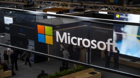 The Microsoft company logo is a reflection of people walking around in suits.