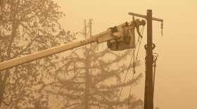 Utility worker repairing a power pole amid a hazy sky. 