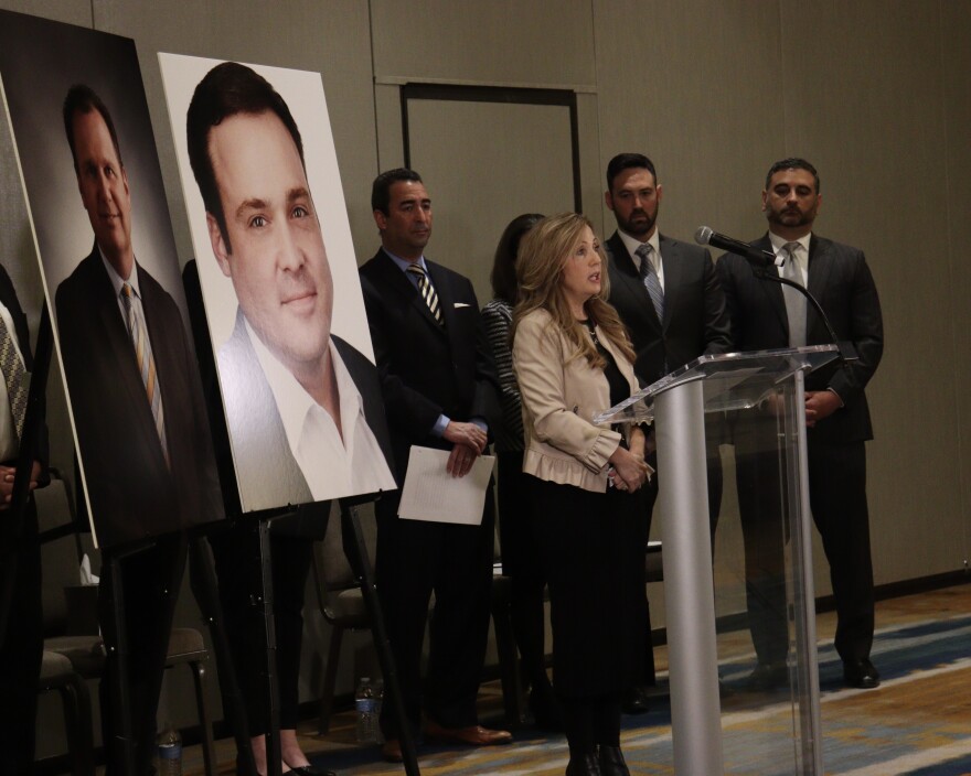 Karen Tutt speaks at a podium in front of pictures of victims of the Old National Bank mass shooting.