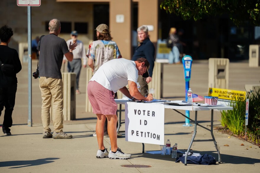 A person signs one of several different petitions at a vote center at the Huntington Beach Central Library in Huntington Beach on Nov. 4, 2025.