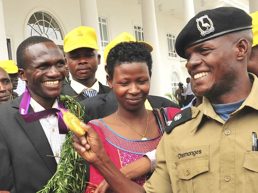 A Ugandan Army officer admires Kiprotich's gold medal at the president's residence, outside the capital Kampala, on Aug. 15. In the center is Kiprotich's wife, Patricia.