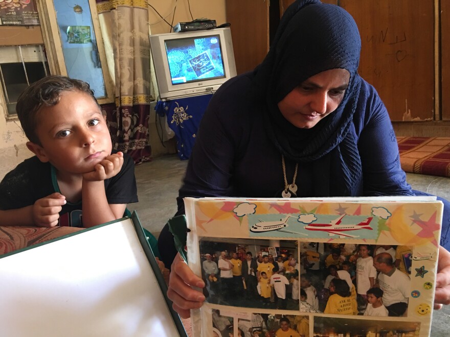 Mustafa's mother Nidhal Aswad looks at a photo album from Mustafa's time in Portland. Mustafa's younger brother Abdul Rahman looks on.