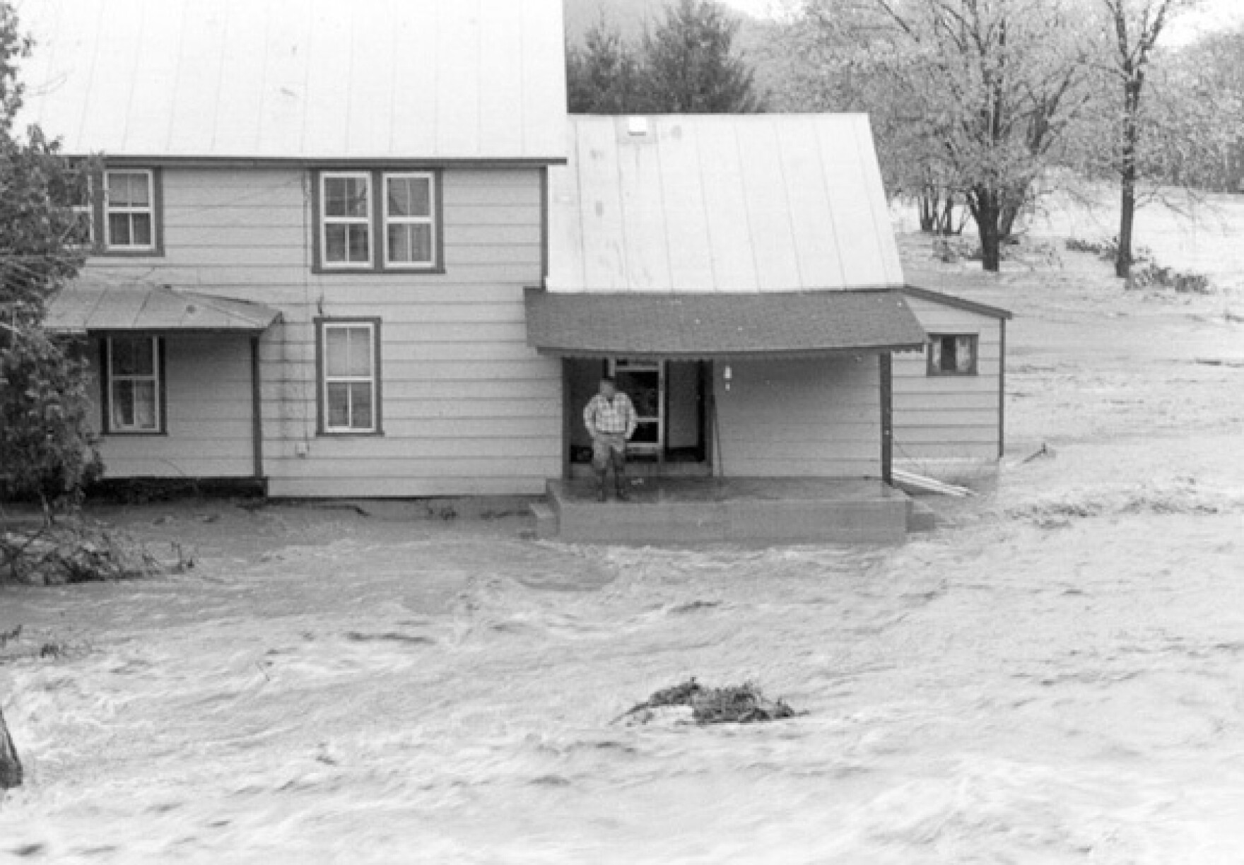 Floodwaters roar past a house in Parsons during the 1985 flood