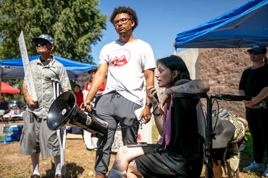 Emma Landis, a protester who was recently shot by a GEO Group employee working at U.S. Immigration and Customs Enforcement's Denver Contract Detention Facility in Aurora, speaks about her experience to a crowd gathered outside of the prison. July 19, 2026.