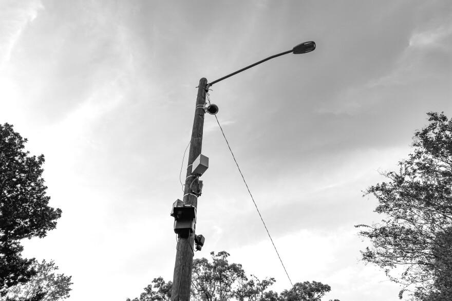 A black and white photo shows surveillance equipment on a utility poll in Birmingham.
