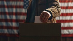 Picture of man dropping off ballot in election.