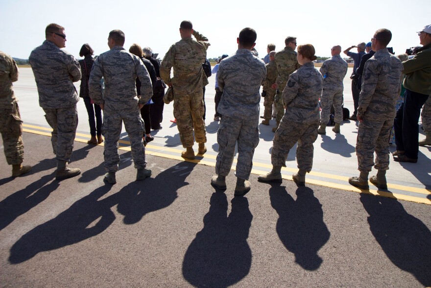 Military members cast shadows on a tarmac. 