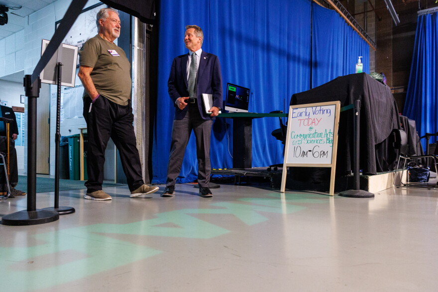 Michigan State University President Kevin Guskiewicz, right, enters an early voting site in WKAR's Studio A on Oct. 21, 2026.