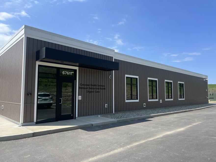 The exterior of a gray-sided medical building with four windows and a front door. 