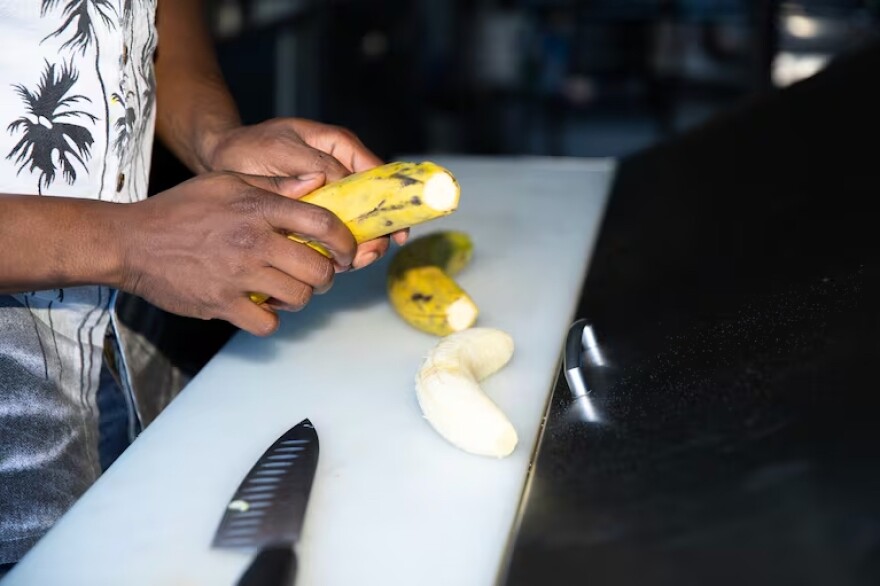 A close-up of a pair of hands peeling a plantain