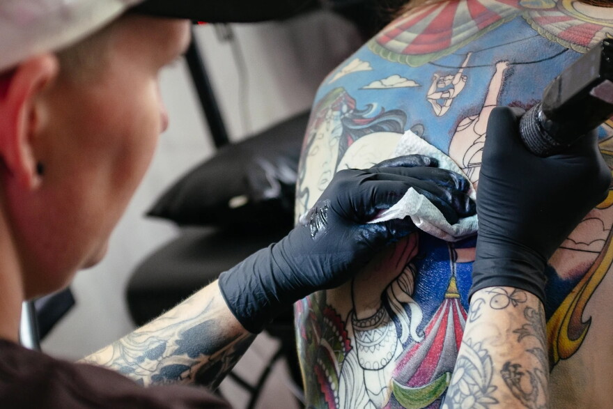 a close-up of a person putting a tattoo on another person's back