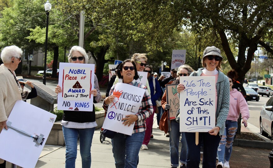 A trio of protestors marching to Innes Park during the No Kings protest.