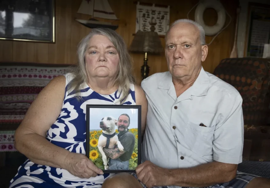 Joseph and Kelly Barrett hold a photo of their son Dennis in their East Alton home July 16, 2026.