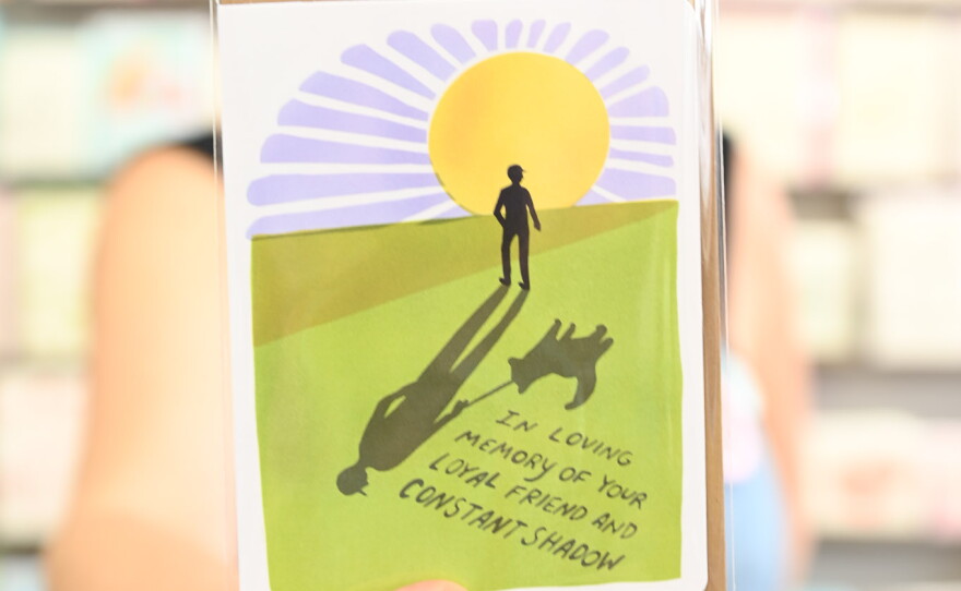a woman holds a pet sympathy card that reads "In loving memory of your loyal friend and constant shadow"
