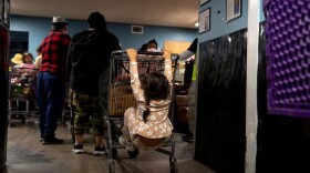 A child plays on her mother’s shopping cart in line at the Ecumenical Ministries of Oregon’s Northeast Emergency Food Program food bank in Portland, Ore., on Tuesday, Oct. 21, 2025.