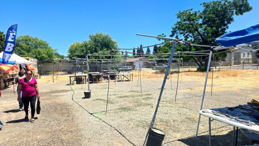 Photo of empty stalls and few people at a designated swap meet area.