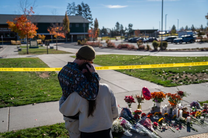 Kyle Ketchum, left, and Christina Edwards hold each other as they look at a makeshift memorial in front of Silver Rail Elementary School in Bend, Ore., on Oct. 16, 2026.