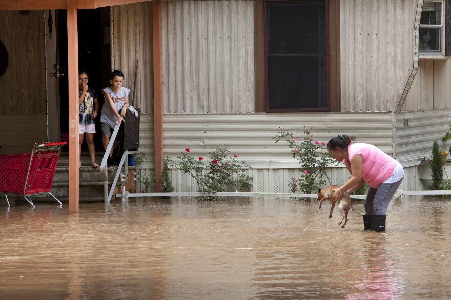 Alejandra Ventura lifts her dog out of the water after the Brazos River topped its banks and flooded a mobile home park in Richmond, Texas, on Tuesday.