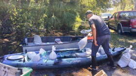 Gabriel Madlang loads sandbags onto his kayak so he can fortify his house on a submerged street in Seminole County, Fla., on Sunday, Oct. 2, 2022. (AP Photo/Mike Schneider)