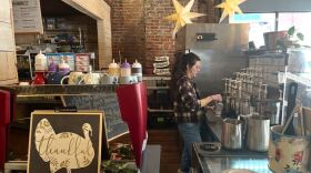 A barista prepares a coffee behind the counter of a shop.