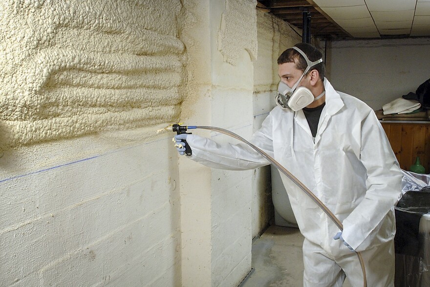 A Weatherization Tech sprays a two-part spray foam on the basement walls and box sill at a home in Yarmouth, Maine.