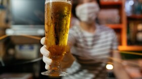 A masked bar owner serves beer during the pandemic. (Getty Images)