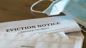 Defaulting renter with facemask receives letter giving notice of eviction from home on wooden table