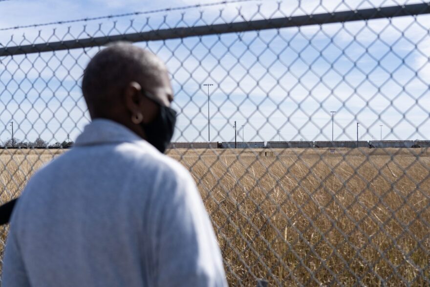 Sandra Edwards looks through a chain-link fence to the Union Pacific Railyard.