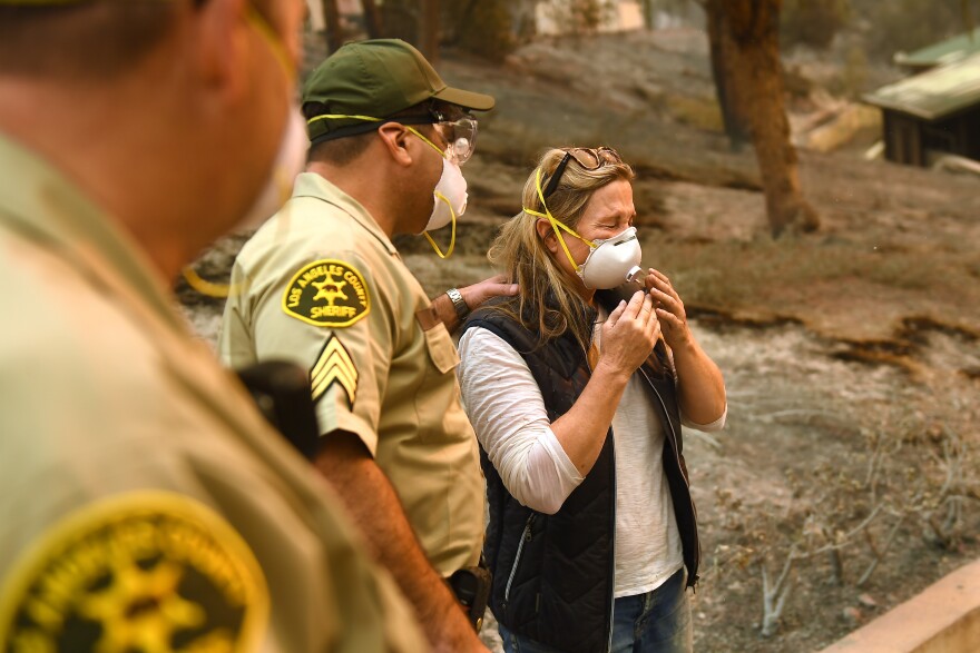 Anne Marie Mueller is consoled by L.A. County sheriff's officer Ernie Ferreras after he notified her that her friends were safe from the Woolsey Fire in Malibu.