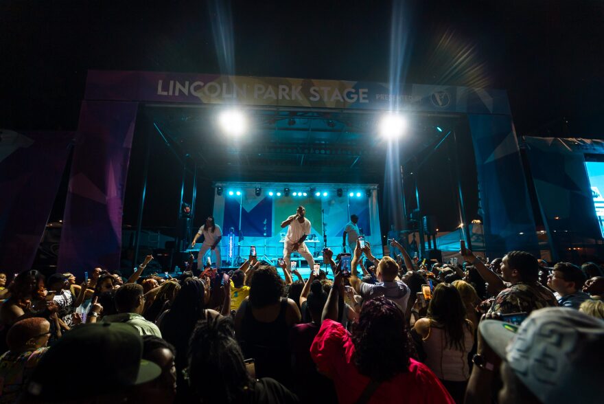 R&B artist Ginuwine performs to a large outdoor crowd at night.