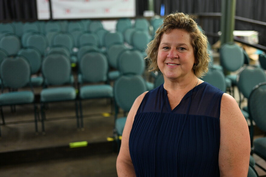 A woman in a navy shirt poses in front of rows of chairs