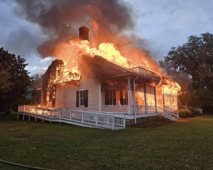 flames come out of the roof of a burning building
