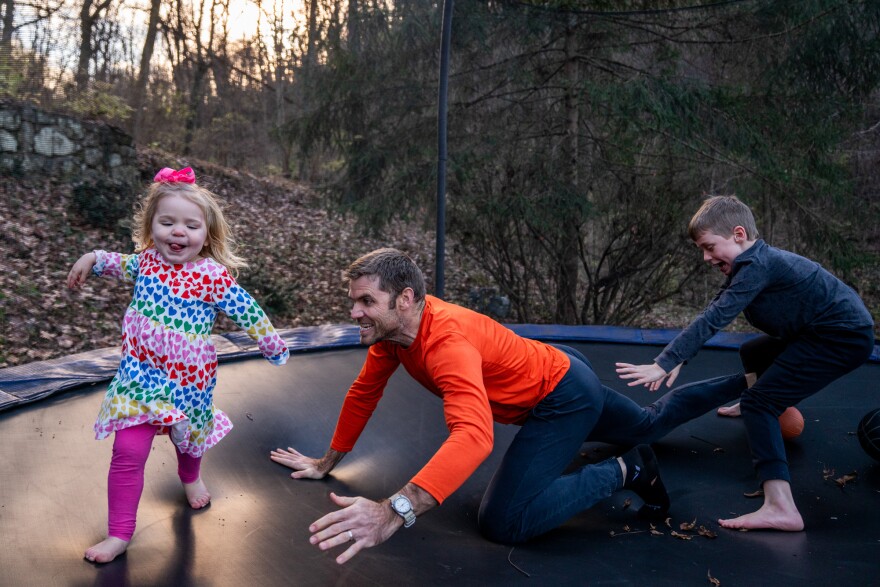 Blake Farmer plays with his kids, Louisa, 2, and Turner, 8, on the trampoline in their backyard in Nashville, Tenn. After Thanksgiving, the family all had breakthrough COVID cases, resulting in a couple weeks spent at home. The trampoline served as a distraction for the kids, Farmer says.