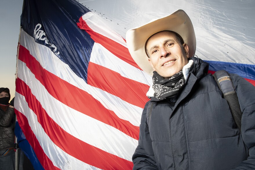  Mexican artist Roberto Marquez. The flag he carries is 25 feet long and is missing its stars, which he says is a commentary on immigration policy in the United States.