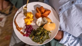 A person standing holds a plate of Thanskgiving food 