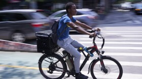 A delivery worker rides a motorized bicycle in New York, Tuesday, July 25, 2023.