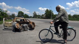 Oleksandr Breus, a Ukrainian and onetime French legionnaire, was killed next to his car during the Russian invasion. Oleksandr Holod, who says he witnessed it from his window, describes events as he rides his bike past the charred remains of the vehicle near Nova Basan, Chernihiv Oblast, Ukraine on June 28.