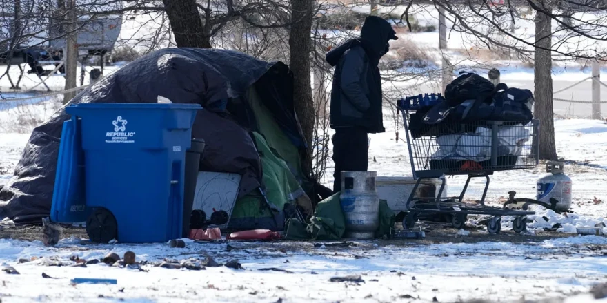 A homeless person checks a cart in front of a tent during a cold day in Chicago, Thursday, Jan. 22, 2026.