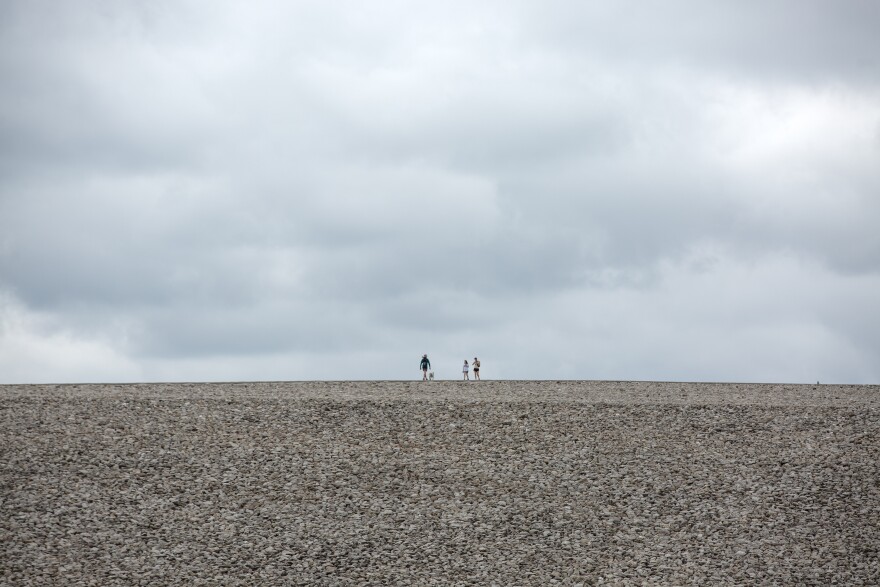 People walk atop a stone-covered landfill on Thursday, July 13, 2023 at the Dept. of Energy’s Weldon Spring Site Interpretive Center in St. Charles County. The landfill was the backdrop for a press conference conducted by politicians and local activists, regarding new reporting on ongoing radioactive contamination in the St. Louis area. During the press conference, those speaking said that they held it at the landfill intentionally, as it had previously been a site of radioactive contamination. 