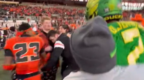 In a still from a video shot at Reser Stadium, a man in OSU garb (center) recoils after being struck by UO player DJ Johnson.