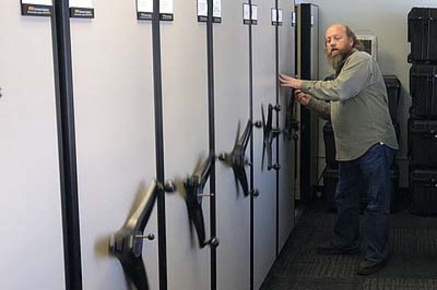 Navy retiree Ted Banks opens the row of cabinets housing Navy Combat Camera's stock of photography equipment in San Diego.