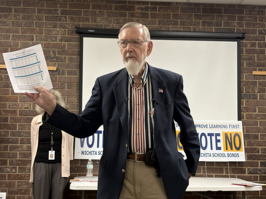 Walt Chappell, a former Kansas school board member and treasurer for the campaign opposing the bond issue, holds up a piece of paper with measures of student proficiency. He argues spending money on new facilities will not improve student outcomes.